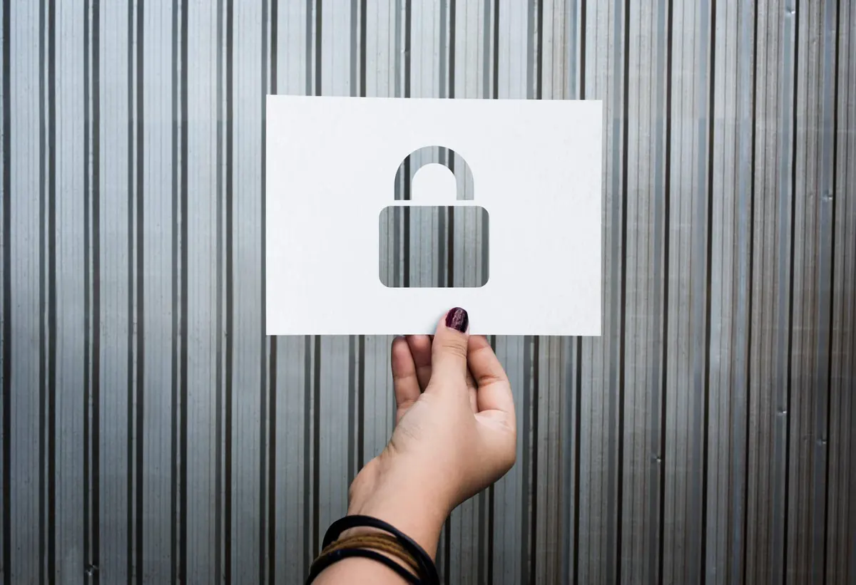 A hand holding up a paper cut-out of a padlock
